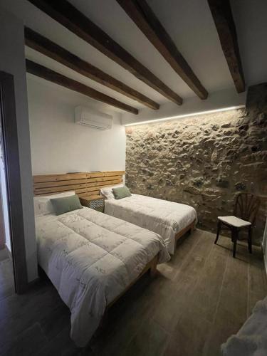 a bedroom with two beds and a stone wall at El Portalet de Can Rialla in Santa Pau
