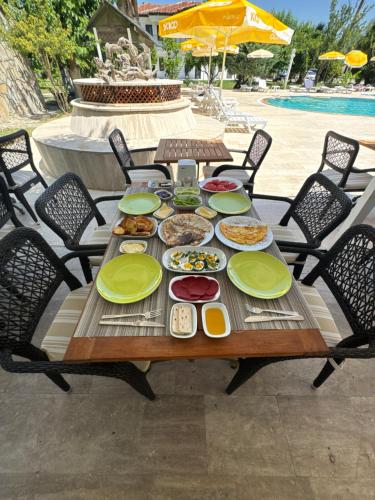 a table with plates of food on it next to a pool at Club Mel Holiday in Ortaca