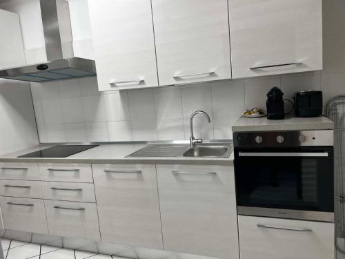 a kitchen with white cabinets and a sink at La casa Bianca di Luca in Fiumicino