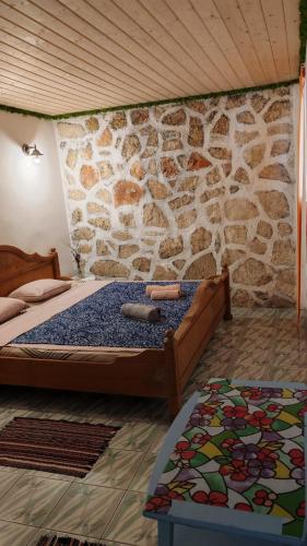 a bedroom with a bed and a stone wall at Casutadinvama in Vama Veche
