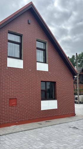 a red brick building with two windows on it at Jaukus butas Pėžaičiuose 