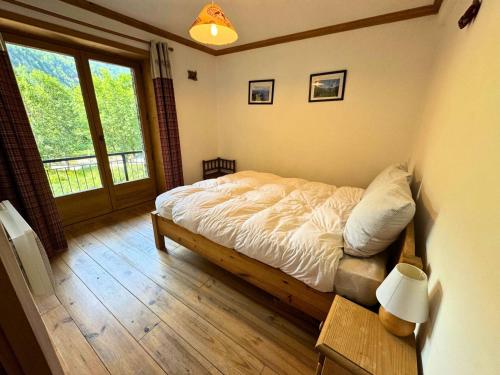 a bedroom with a bed and a large window at Chalet Chardons - Chalet Authentique proche des 3 Vallées MAE-3704 in Saint-Martin-de-Belleville