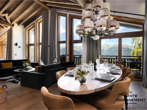 une salle à manger avec une table et un lustre dans l'établissement Résidence Canyon Lodge - Chalet d'exception dans le quartier du Belvédère MAE-2454, à Courchevel
