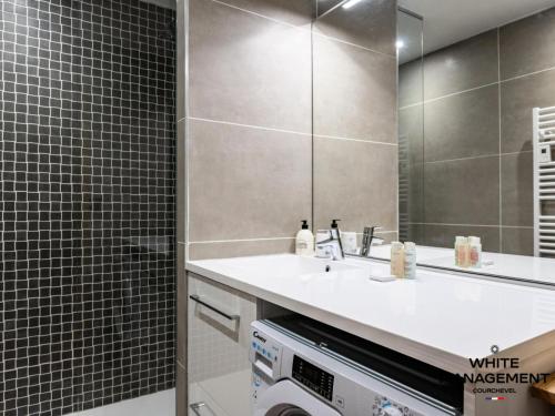 une salle de bain avec un lavabo et une machine à laver dans l'établissement Résidence L'ourse Bleue - Appartement familial rénové au pied des pistes MAE-8344, à Courchevel