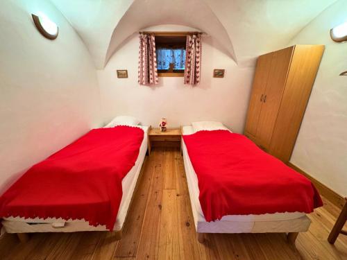 - 2 lits dans une chambre avec des draps rouges dans l'établissement Chalet Chardons - Appartement situé à 4km des pistes MAE-6451, à Saint-Martin-de-Belleville