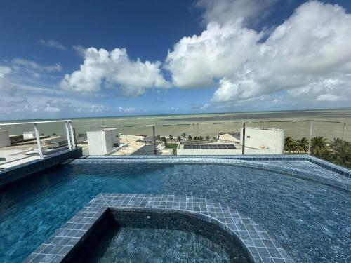 a swimming pool on top of a building with the beach at Studio Mobiliado com Vista Mar a 30m da Praia de Ponta de Campina in Cabedelo