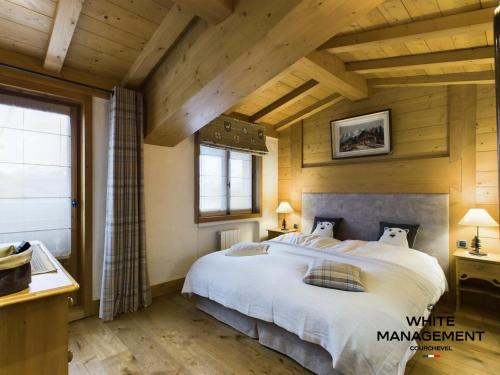 une chambre avec un grand lit dans une pièce avec des plafonds en bois dans l'établissement Résidence Amadablam - Charmant appartement au coeur de Courchevel 1850 MAE-3781, à Courchevel