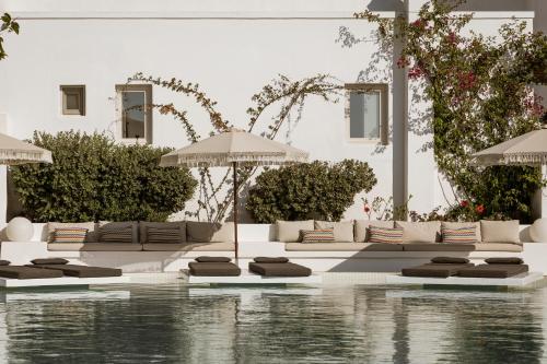 a pool with lounge chairs and an umbrella next to a building at AMĀRIA Beach Resort by NOMÉE Hospitality Group in Kamari