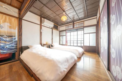 two beds in a room with wooden floors at Sanada Maru in Kaizuka