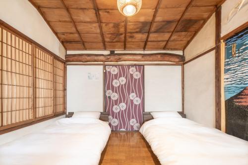 two beds sitting in a room with a ceiling at Sanada Maru in Kaizuka