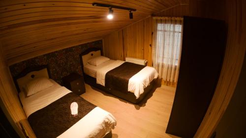 a bedroom with two beds in a room with wooden walls at Meric Hotel in Uzungöl