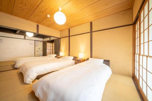 two beds in a room with wooden ceilings and windows at Sanada Maru in Kaizuka