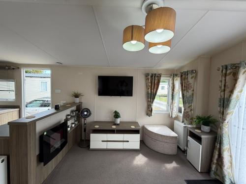 a small living room with a tv and a table at Modern 6 birth caravan Hunstanton Norfolk in New Hunstanton
