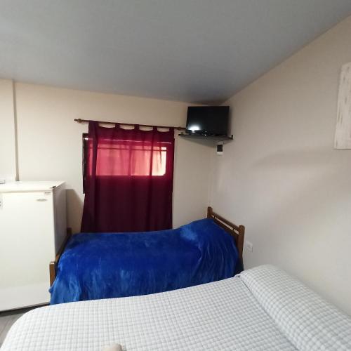 a bedroom with two beds and a red curtain at Complejo Corrientes Depto 4 in Jesús María