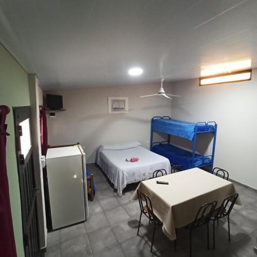 a room with a bed and a table and a refrigerator at Complejo Corrientes Depto 4 in Jesús María