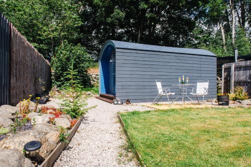 a blue shed with a table and chairs in a yard at Loch Ness Hideaway Pod in Lewiston