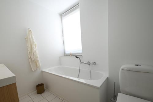 a white bathroom with a tub and a window at Panorama by Villa Mer, Luxury apartment with two bathrooms, two balconies and stunning sea view in Cadzand