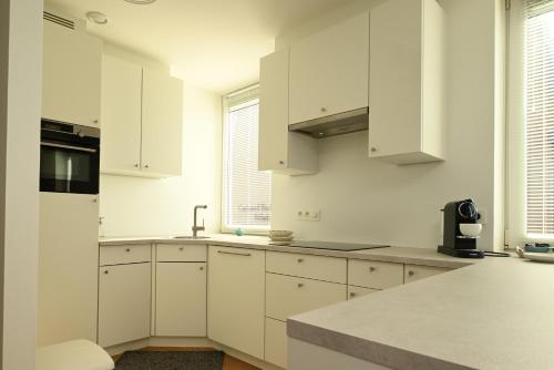 a white kitchen with white cabinets and white appliances at Panorama by Villa Mer, Luxury apartment with two bathrooms, two balconies and stunning sea view in Cadzand