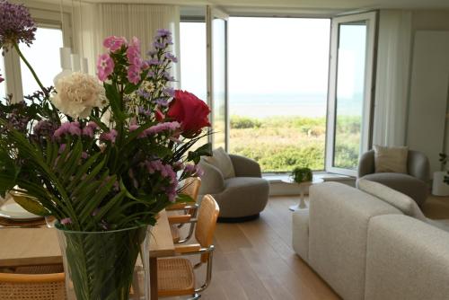 a living room with a vase with flowers in it at Panorama by Villa Mer, Luxury apartment with two bathrooms, two balconies and stunning sea view in Cadzand