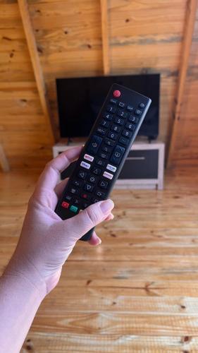 a person holding a remote control in their hand at Chalé do Lago in Toledo