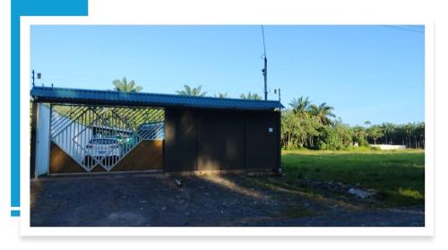 a building with a gate in a field at Villa Blue Vacations in Parrita
