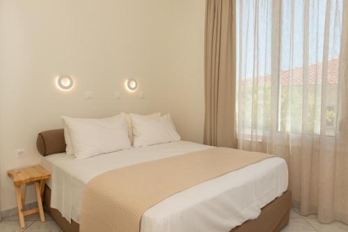 a bedroom with a large bed with a window at Ellinas Hotel in Chrysi Ammoudia