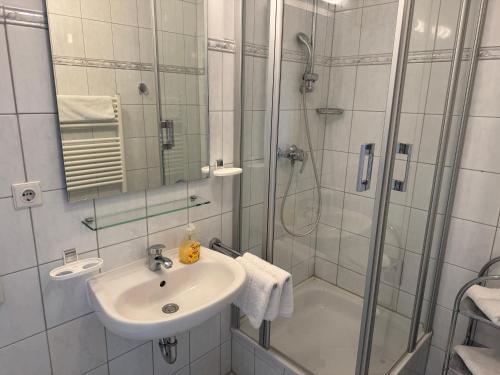 a white bathroom with a sink and a shower at Ferienwohnung Möwe mit Balkon und einem Strandkorb im Sommer in Zempin