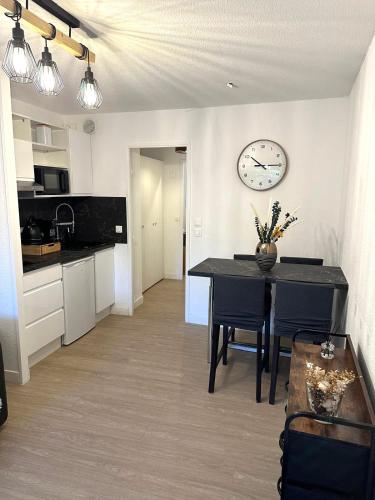 une cuisine avec une table et une horloge au mur dans l'établissement Marina Baie des Anges, à Villeneuve-Loubet