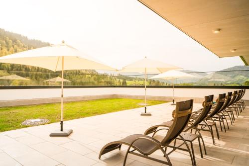 a row of chairs and umbrellas on a patio at Ferienwohnungen Guthof in Schattwald