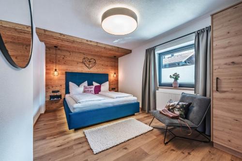 a bedroom with a bed and a chair and a window at Landhaus Rohrmoser in Zell am Ziller