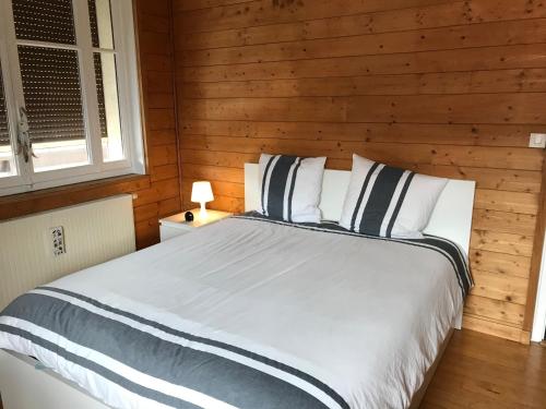 - une chambre avec un lit et un mur en bois dans l'établissement Chambres à Sallanches, à Sallanches