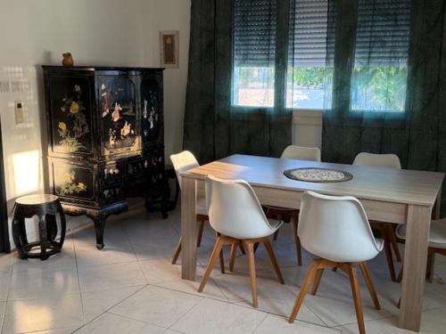 a dining room with a wooden table and white chairs at Villa avec piscine in Le Crès