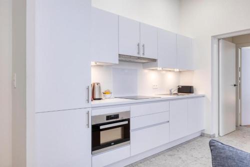 a kitchen with white cabinets and a stove top oven at The Ghentian Suites by Domani Hotels in Ghent