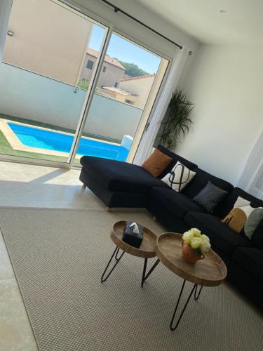 - un salon avec un canapé noir et 2 tables dans l'établissement villa 8 personnes clim, piscine, parking, à Piolenc