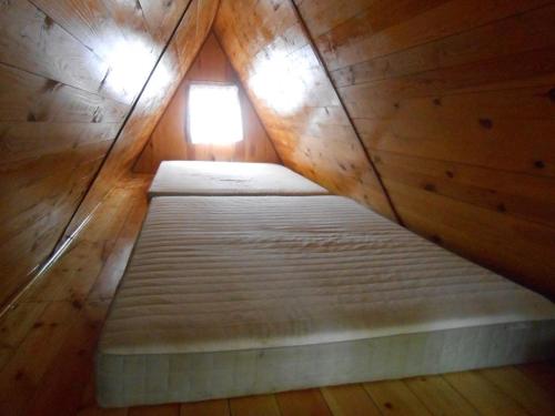 a small bed in a wooden room with a window at Domek letniskowy "BRDA" - Ostoja Ślesin in Półwiosek Stary