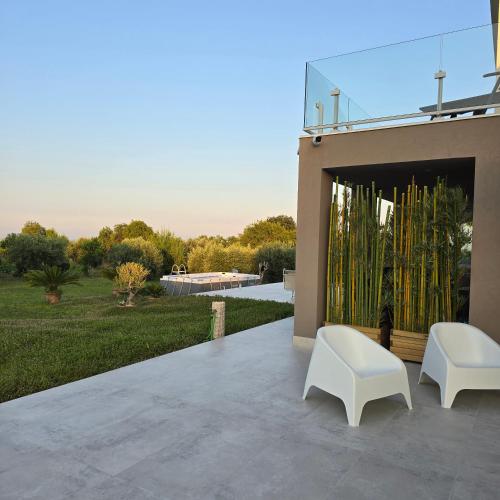 a patio with two white chairs and a fireplace at I Secolari di Giulia 2 in Avola
