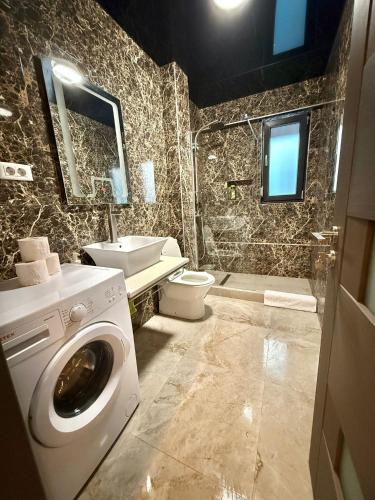 a bathroom with a washer and a toilet and a sink at Happy Apartments Mamaia Nord 2 Camere in Mamaia Sat/Năvodari