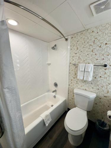 a white bathroom with a toilet and a tub and a toilet at Wyndham Houston Hobby Airport in Houston