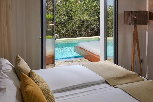 a bedroom with a bed and a swimming pool at Sentido Kyknos Beach Adults Only in Malia