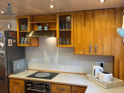 a kitchen with wooden cabinets and a counter top at Ferienwohnung 70qm - Natur, Fitness & SUP am Fluss in Damm