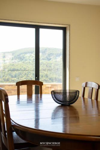 a wooden table with two chairs and a large window at Casa da Portelinha in Castelo de Paiva