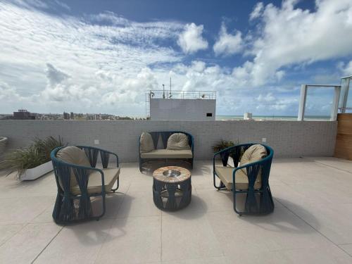 a patio with chairs and a table on a roof at Studio Mobiliado com Vista Mar a 30m da Praia de Ponta de Campina in Cabedelo