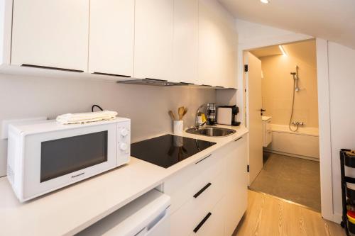 a white kitchen with a microwave and a sink at Hostel Charino in Pontevedra