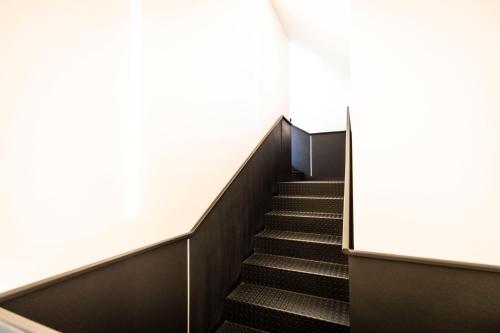 a staircase in a building with black stairs and white walls at Hostel Charino in Pontevedra