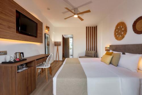 a hotel room with a bed and a desk and a tv at Sentido Kyknos Beach Adults Only in Malia