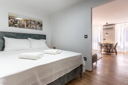 a bedroom with a large white bed with a table at Ilir Apartman in Cres