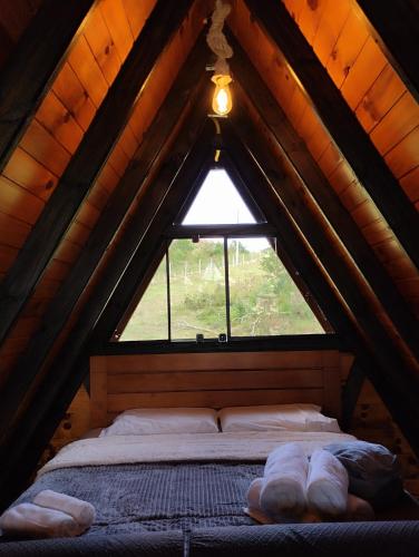 a bed in a wooden attic with a window at Rancho dos lagos in Campo Alegre