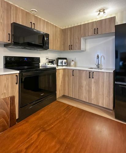 a kitchen with black appliances and wooden cabinets at Prestige Prince George Lodge in Prince George