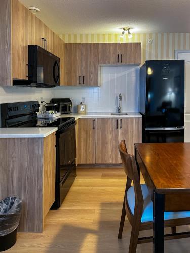 a kitchen with wooden cabinets and a wooden table with a dining room at Prestige Prince George Lodge in Prince George