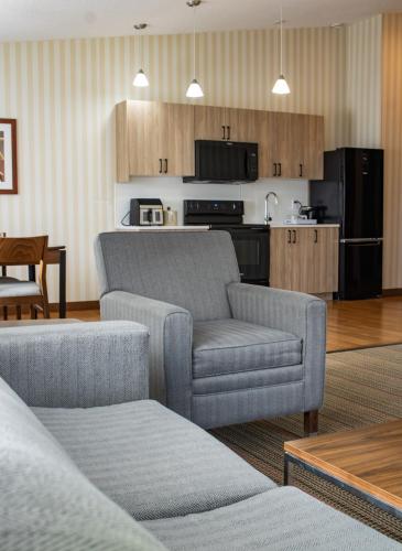 a living room with a couch and a chair and a kitchen at Prestige Prince George Lodge in Prince George